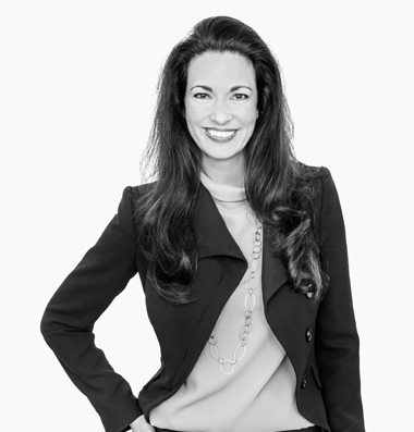 GET | Team Bella Tumulka Frau in Blazer lächelt mit Hand in der Hüfte freundlich