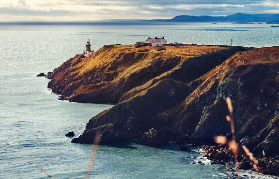 GET | Sprachreise in Irland Landzunge im Meer mit Leuchtturm und kleinem Häuschen